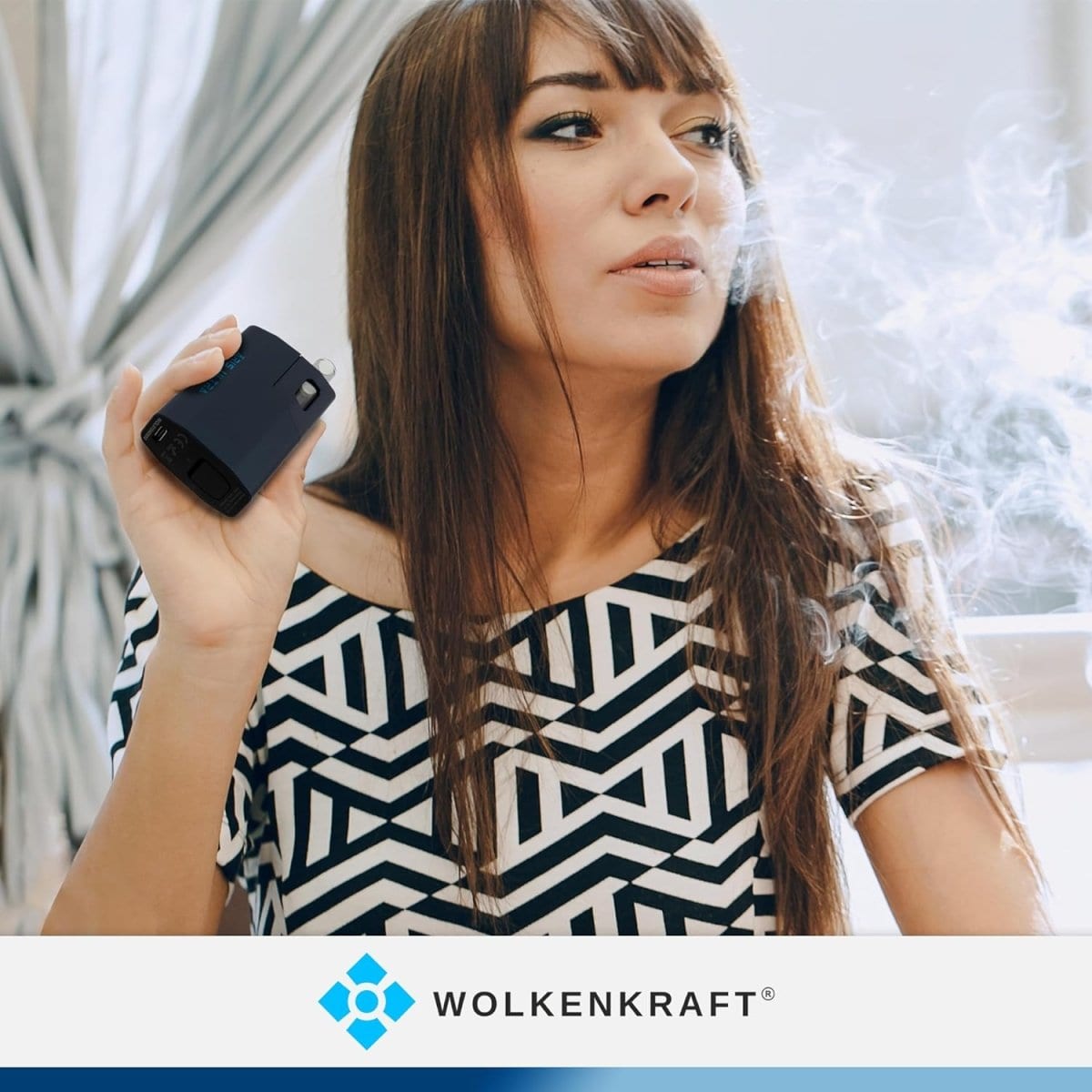 Frau genießt den Wolkenkraft Äris Ultra Vaporizer in Dunkelblau, umgeben von Dampf vor einem sonnigen Fenster.